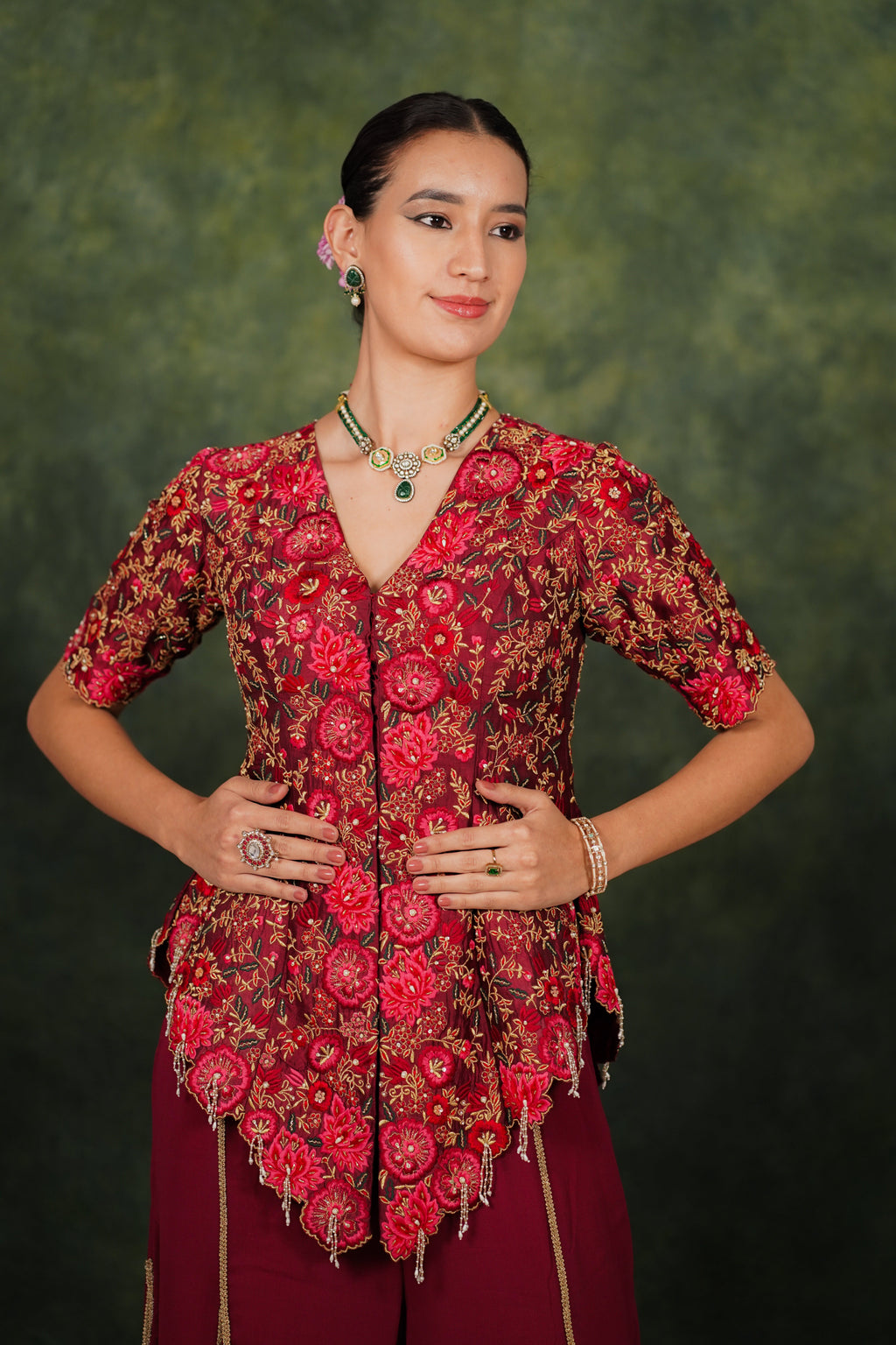 Woman wearing a red and brown patterned blouse with a green background